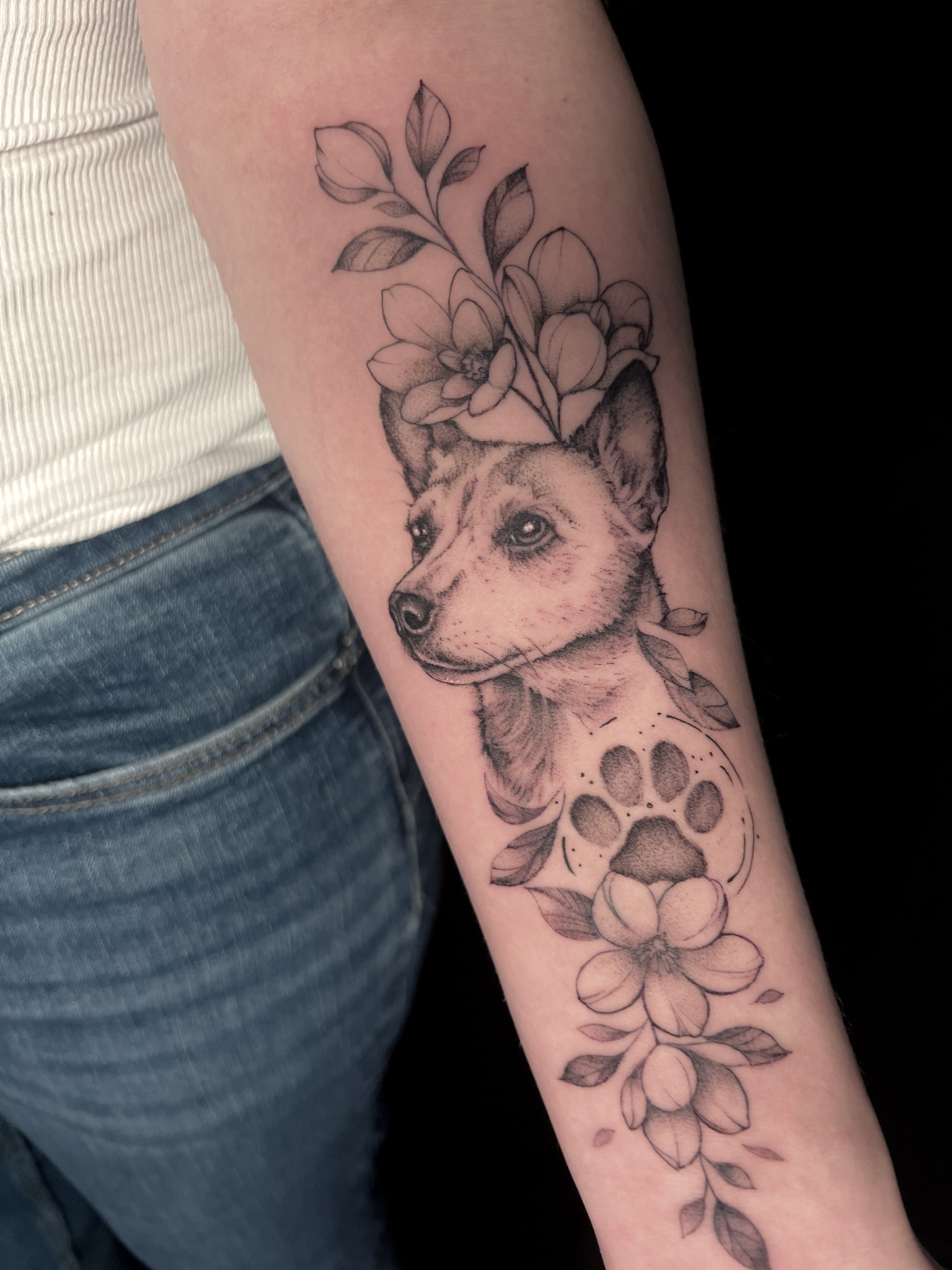 Feines Tattoo eines Hundes mit Blumen auf dem Unterarm